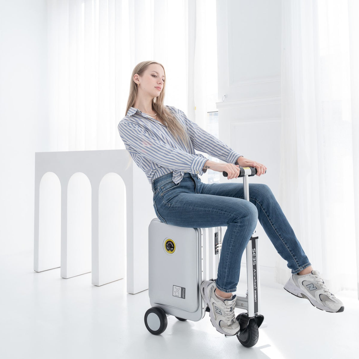 Frau fährt sitzend auf dem Airwheel SE3SL in Silver – der Koffer zum Fahren